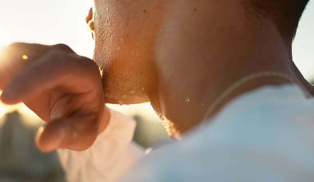 Man in white shirt wiping sweat from his chin.